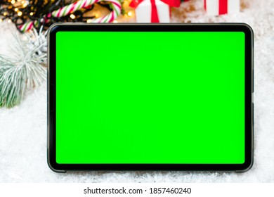 Tablet With Chromo Key On The Screen On The Snow Under Christmas Tree. 