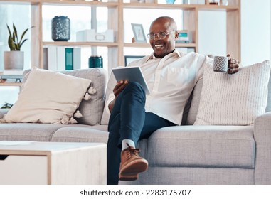 Tablet, coffee break and relax with a black man on the sofa, sitting in the living room of his home or office. Business, tech or research with a male employee reading an online article while chilling