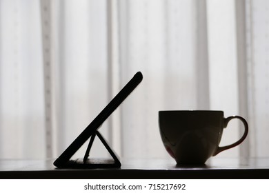 tablet and coffee cup on the table in silhouette style