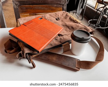 Tablet, Coffee, and Messenger Bag on the Table at a Coffee Shop. Remote Working. - Powered by Shutterstock