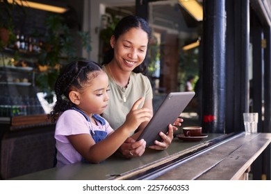 Tablet, coffee shop and happy mother with her child reading the online menu before ordering. Technology, internet and mom on a date with her girl kid with a touchscreen mobile device in a cafe. - Powered by Shutterstock