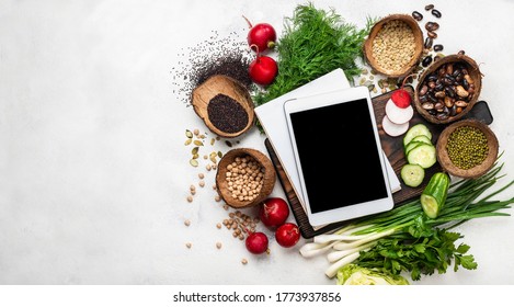 Tablet computer with blank screen and notebook with fresh vegetables on the chopping board. Top view with place for text. - Powered by Shutterstock