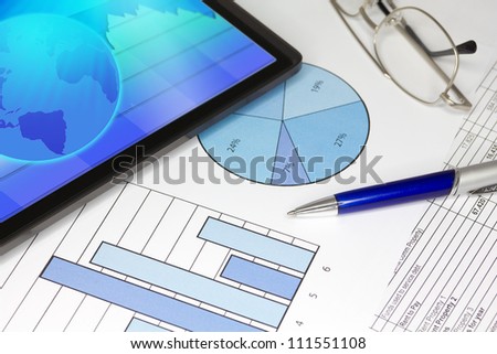  Tablet Computer in ipade style with Blue Pen Spectacles Figures and Graphs