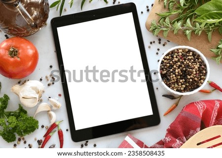 Tablet computer with mock up white screen in kitchen with food flat lay background. Online grocery shopping, takeout, food delivery app ads or recipe concept.