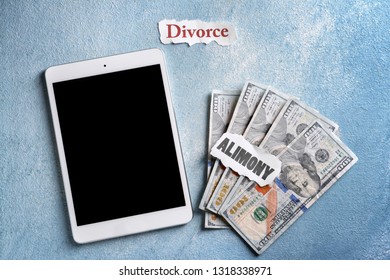 Tablet computer, money and papers with text ALIMONY and DIVORCE on table