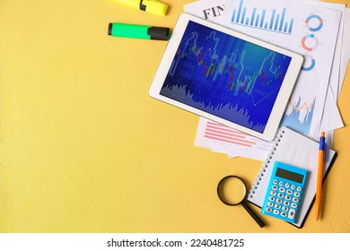 Tablet computer with stock data, documents and calculator on yellow background. Finance trading