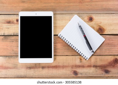 Tablet device, pen and note book on wooden workspace table