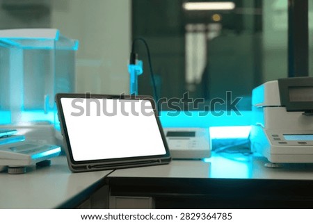 A tablet displaying a blank white screen sits on a lab bench surrounded by analytical instruments, ideal for pharmaceutical quality control and research technology concepts.