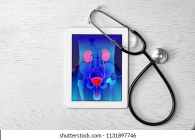 Tablet Displaying Urinary System And Stethoscope On Wooden Background. Urology Concept