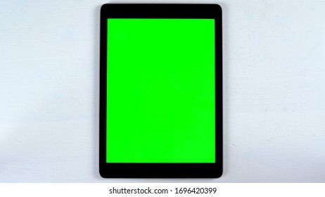 A tablet with a green screen lies on the table. Chroma Key on Gadget Screen.