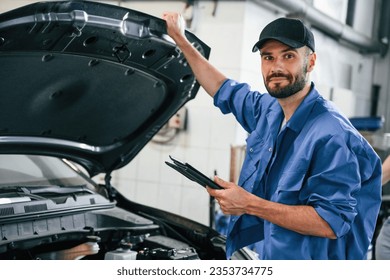 With tablet in hands. Auto mechanic working in garage. Repair service. - Powered by Shutterstock