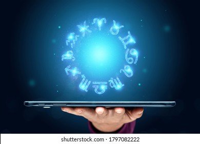 Tablet and hologram 12 zodiac signs, horoscope signs, neon on blue background. The concept of fate, predictions, fortune teller. copy space