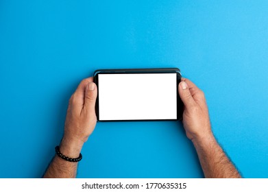 Tablet In Human Hands, White Screen, Your Picture Here, With Blue Background. Top View