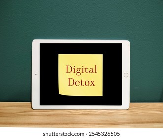 Tablet mobile computer with stick note written Digital Detox  - take a break from smartphone or unplugging from technology to reconnect with your inner self and regain control over your life