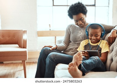 Tablet, mother and kid with headphones on sofa for digital media, streaming service and entertainment. Happy, black family and boy with tech at home for online movie, connectivity or bonding together - Powered by Shutterstock