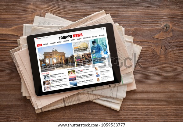Tablet with news website on stack of newspapers. All\
contents are made up.