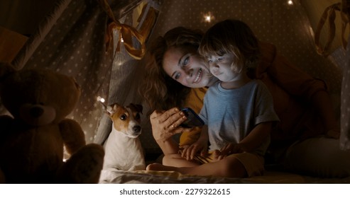 Tablet, night a mother reading to her child in a tent while camping in the bedroom of their home together. Caucasian family, story for kids with a woman storytelling to her kid at bedtime for bonding - Powered by Shutterstock