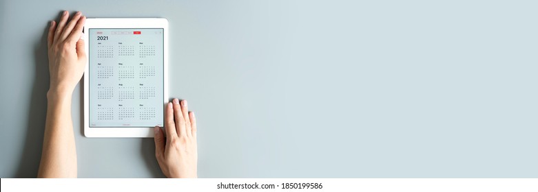 A Tablet With An Open Calendar For 2021 Year In A Womans Hands On A Gray Background. Banner. Space For Text
