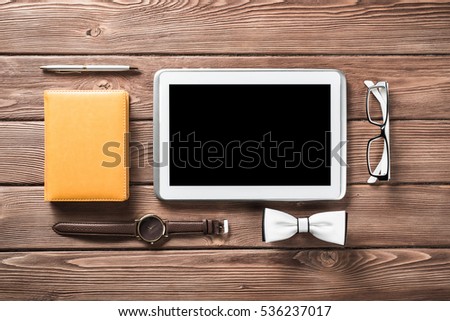 Tablet pc computer wallet eyeglasses bowtie and wristwatch on table