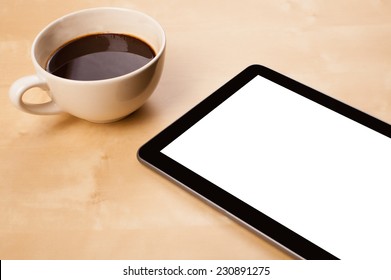 Tablet pc with copy space and a cup of coffee on a wooden work table close-up