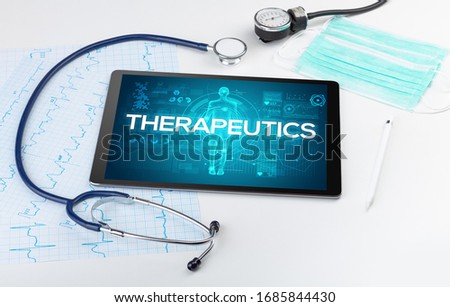 Tablet pc and doctor tools with THERAPEUTICS inscription, coronavirus concept