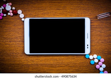 Tablet pc with medical objects on a desk as a metaphor for electronic diagnostic or healthcare mobile apps. Medical background