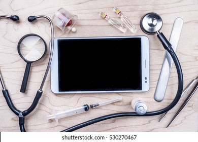 Tablet pc with medical objects on a desk as a metaphor for electronic diagnostic or healthcare mobile apps. Medical background - Powered by Shutterstock