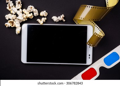 Tablet Pc On Dark Background With Attributes Of Cinema. Visual Metaphor For Content Consumption - Films And Media On A Mobile Device.