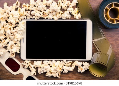 Tablet Pc On Wood With Attributes Of Cinema. Visual Metaphor For Content Consumption - Films And Media On A Mobile Device.