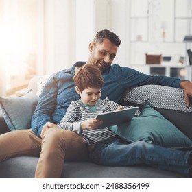 Tablet, relax and father with child on sofa playing online video game in living room at home. Happy, bonding and dad teaching boy kid esports on digital technology for fun together in lounge at house - Powered by Shutterstock