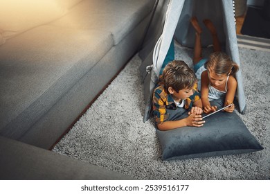 Tablet, relax and siblings in tent in home playing online educational game for learning. Rest, digital technology and young children watching video in blanket fort for fun in living room at house. - Powered by Shutterstock