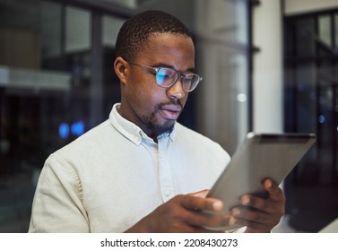 Tablet Research, Night Planning And Businessman Working On Email On The Internet While In A Dark Office At Work. Corporate African Employee Reading Communication Online On Tech While Doing Overtime