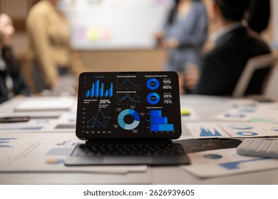 A tablet with a screen showing a graph of data. The tablet is on a table with other papers and a person is standing behind it