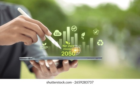 Tablet showing data chart with Net Zero 2050 mission text and green eco icons. Hand holding stylus. Concept of digital analytics for sustainability and CO2 reduction. - Powered by Shutterstock - Get 15% off with code: PIKWIZARD15