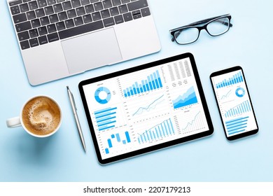 Tablet and smartphone with charts and reports on desk. Top view flat lay - Shutterstock ID 2207179213