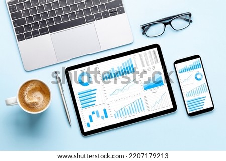 Tablet and smartphone with charts and reports on desk. Top view flat lay