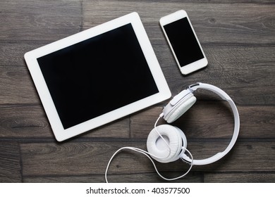 Tablet and smartphone on an old wood with headphones - Powered by Shutterstock