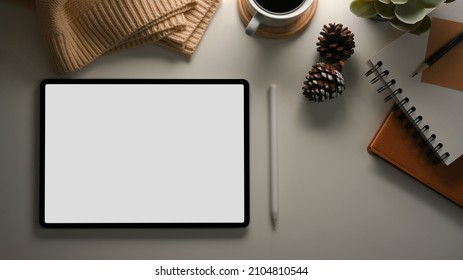 Tablet touchpad computer white screen mockup on a table with cozy and warm decorations stuff. Feminine worktable concept