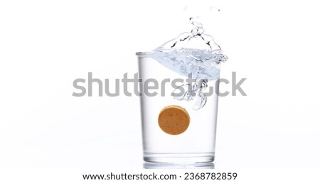 Tablet or Vitamin Falling and Dissolving into a Glass of Water against White Background
