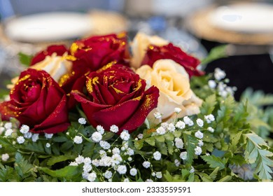 Tabletop floral arrangement, bouquet of red and white roses with gold glitter. - Powered by Shutterstock