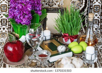 Tabletop with Haft-seen elements for Nowruz: sonbol (hyacinth), sabzeh (grass), seeb (apple), somaq (sumac powder), seer (garlic), serkeh (vinegar), goldfishes, flowers, coins, burning candles etc.