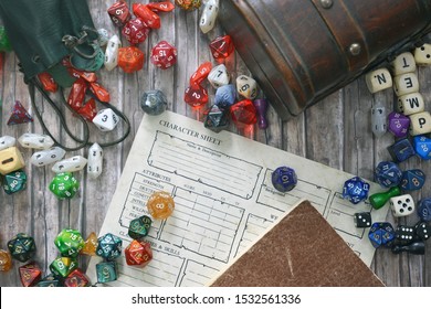 Tabletop Role Playing Flat Lay With Colorful RPG And Game Dices,  Character Sheet, Rule Book And Treasure Chest On Wooden Desk