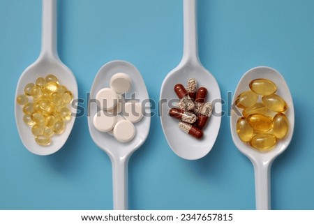 Tablets, capsules, dietary supplements, vitamins on white spoons. Medical background with pills