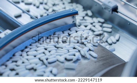 Tablets and Capsules Manufacturing Process. Close-up Shot of Medical Drug Production Line. White Painkiller Pills are Moving on Conveyor at Modern Pharmaceutical Factory.