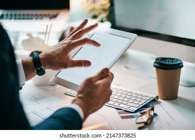 Tablets Are So Helpful In This Day And Age. Shot Of An Unrecognizable Businessman Browsing On His Digital Tablet While Being Seated In The Office During The Day.