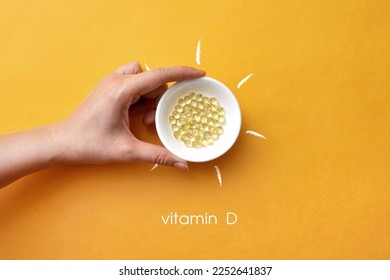 Tablets on a plate inside a picture of the sun and the inscription: vitamin D - Shutterstock ID 2252641837
