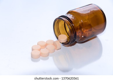 Tablets Pills Spilling Out Of Pill Bottel On White Background.