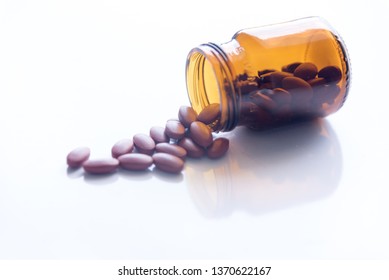 Tablets Pills Spilling Out Of Pill Bottel On White Background.