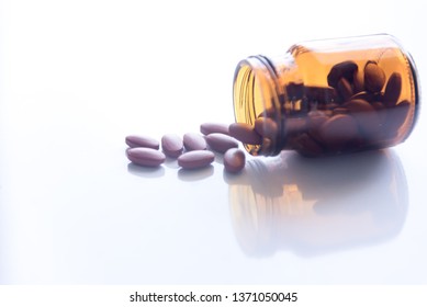 Tablets Pills Spilling Out Of Pill Bottel On White Background.