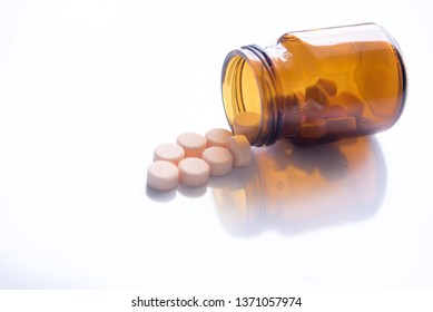 Tablets Pills Spilling Out Of Pill Bottel On White Background.